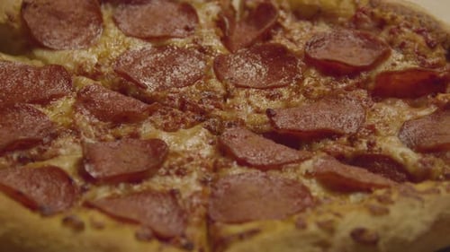 Slice of Pepperoni Pizza being grabbed from whole pizza - close up