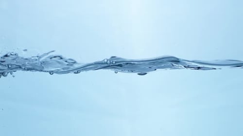 A slow-motion water droplet falls into a still pool, creating concentric ripples that reflect purity