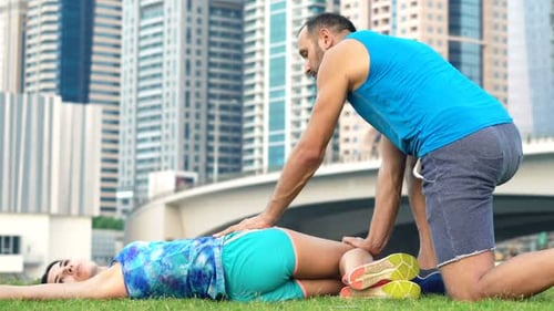 Young Woman Stretching Body in Park with Help of Personal Trainer Active