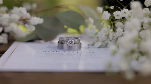 Weddings rings surrounded by babies breath flowers on a wedding invitation.
