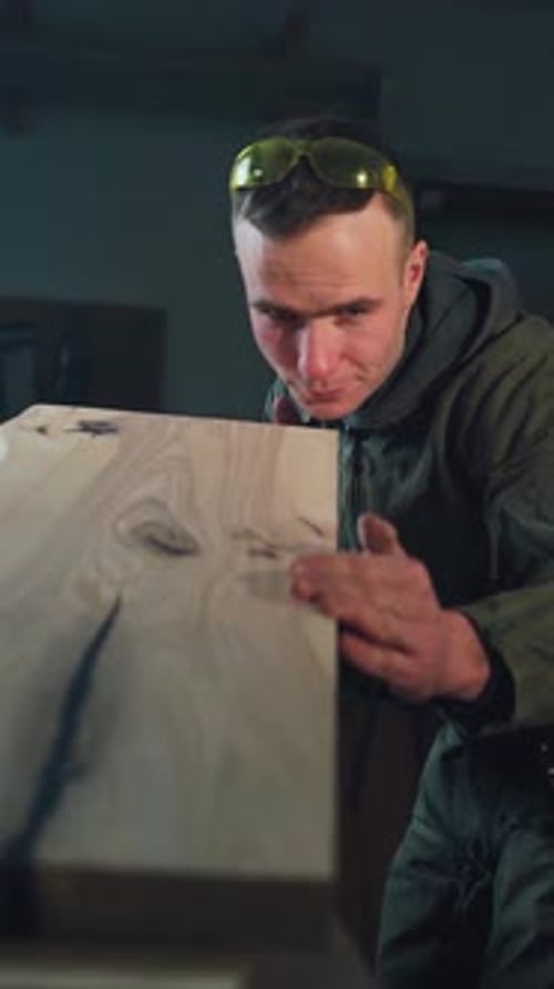 A Young Worker Man Carpenter in a Carpentry Checks the Flatness of a Board in a Wood Furniture