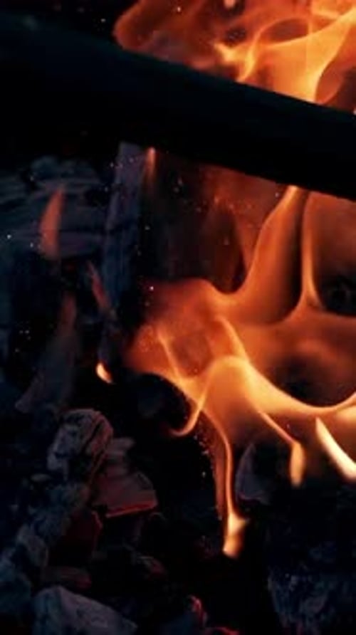 Explosion de flammes avec des étincelles brillantes. Des bûches noires fumées explosent avec une flamme ardente
