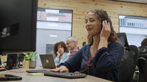 Businesswoman Wearing Headset Working at Computer in Office Business Concept