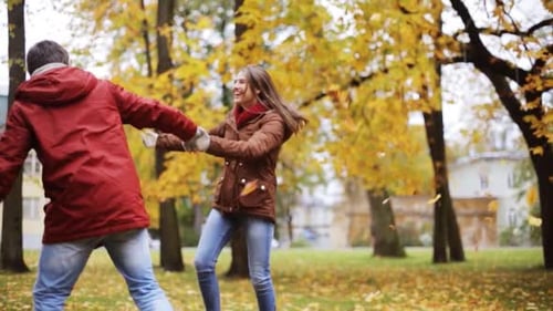 Happy young couple embracing and laughing together in a beautiful autumn park