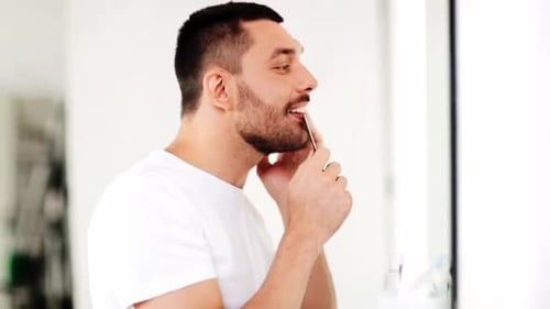 Man Combs His Beard in the Mirror