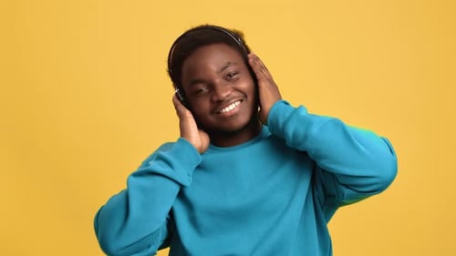 Portrait Smiling African Man in Headphones Dancing Listening Music Posing Isolated on Orange Studio