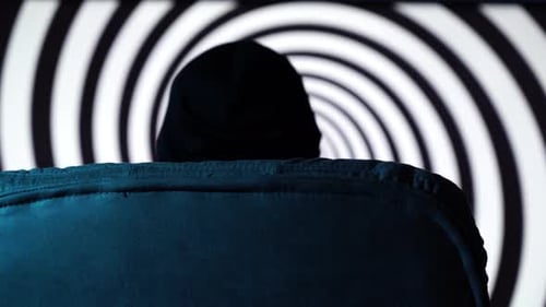 Back View of Evil Man Sitting on Chair with Hypnotic Black Spiral