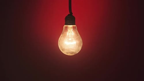 Incandescent Lamp Glows and Flickers on Dark Red Background Place for Text