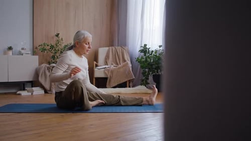 Senior Woman Stretching on Yoga Mat Indoors