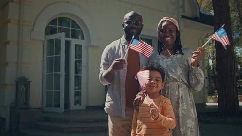Portrait of Happy African American Family with US Flags on Independence Day