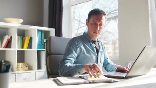 Young Male Entrepreneur Works at Home Office at the Computer Workplace of Freelancer or Student