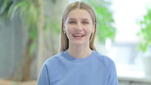 Young Woman Smiling and Waving Hello Indoors