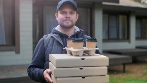 Porträt eines jungen Kurierzustellers, der Pizza in Kartons hält und auf einen Kunden wartet