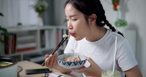 Young Woman Enjoys Food at Home With Chopsticks