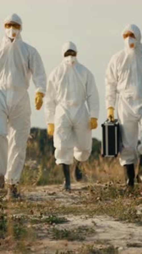 Scientists in Protective Suits Walking Outdoors
