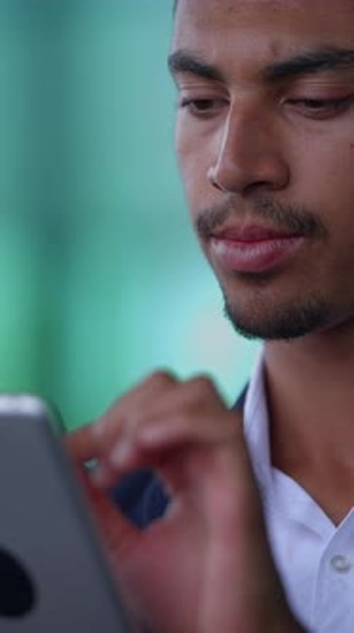 A Focused Young Man Engaged with a Tablet in a Modern Dynamic Office Environment