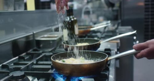 Professional Cook Adds Cheese to Pasta in Pan