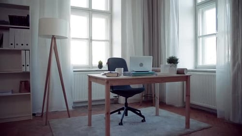 Sunlit home office desk with laptop and plant in slow motion for flexible work