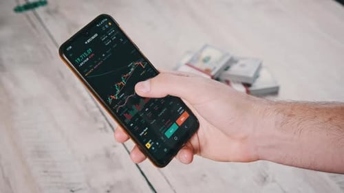Hand Using Trading App on Smartphone with Money