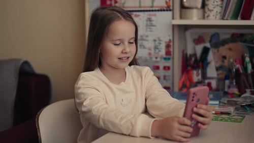 Smiling Girl Using Smartphone Indoors at her Desk