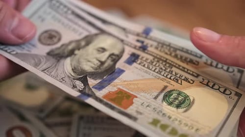 One hand gives money to another hand, close-up on blurred background of wooden table