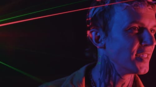 Man Smiles Under Laser Lights in a Club