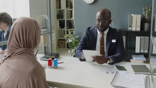 Visa Officer with Tablet Interviewing Muslim Applicant