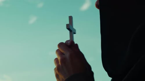 Hands Holding Cross Against Blue Sky