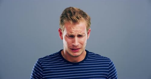 4k video footage of a young man crying against a grey background