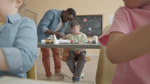 Teacher Making Paper Craft with Kid during School Lesson