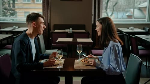 Date in the hotel restaurant dinner man and woman drink white wine in glasses and taste food