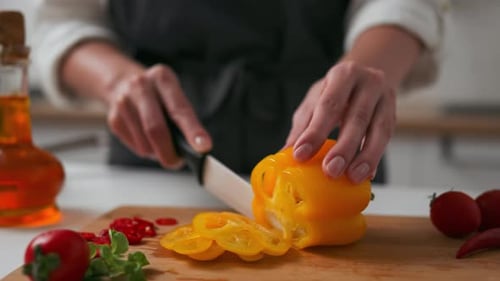 Person cutting yellow pepper in kitchen