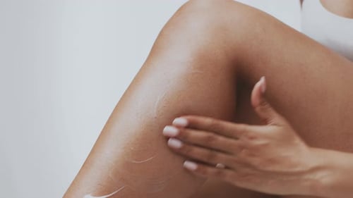 Woman Applies Moisturizing Lotion to Leg