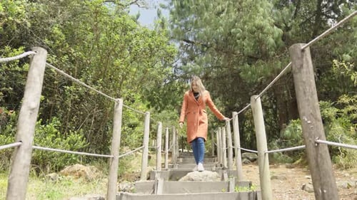 Woman is walking up a set of wooden stairs he image has a peaceful and serene mood in a natural park