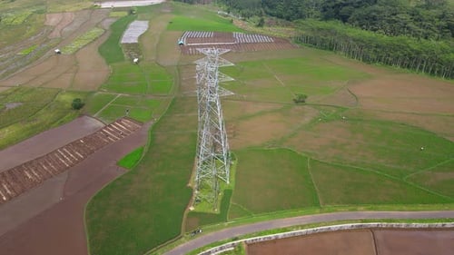 Drone fly near high voltage electricity tower on the middle of rice field