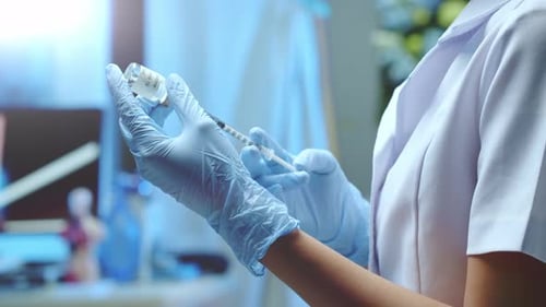 A nurse measures out a dose of COVID vaccine to give a shot to a patient