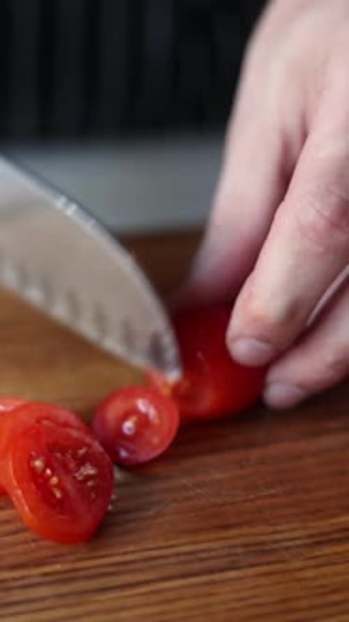 The chef slices tomatoes on a wooden board