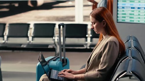 Woman Business Traveler Checking Emails on Laptop in Airport Lounge Corner