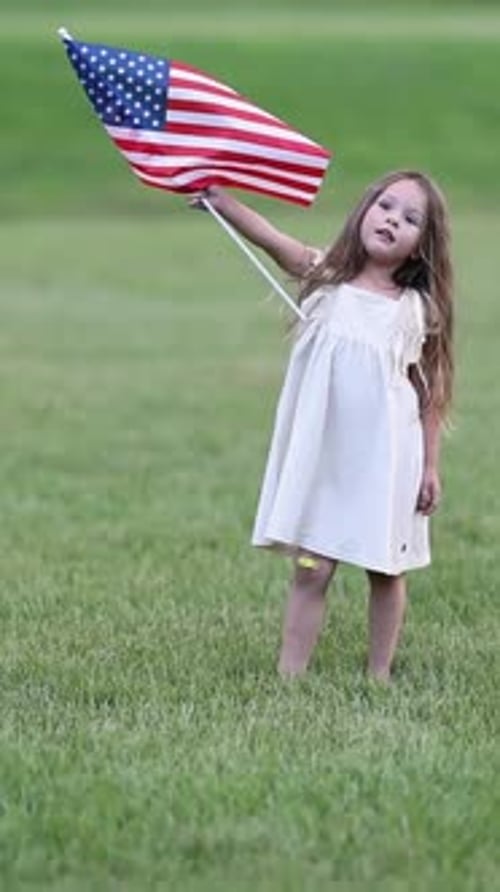 Girl Waves American Flag on Grassy Field