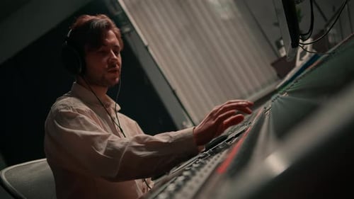 Energetic audio engineer producer working in recording studio mixing tracks on console and hit maker