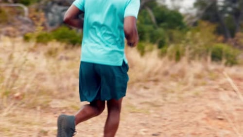 Man Runs on Dirt Path Through Field in Nature
