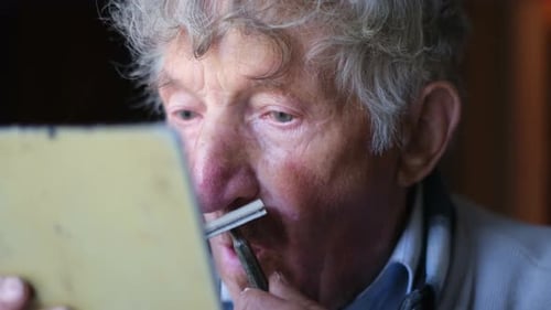Senior Man Shaves Mustache Using Razor and Mirror