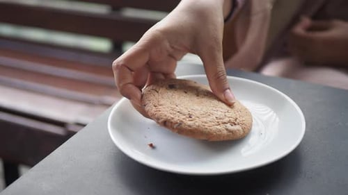 Hand Reaching for Chocolate Chip Cookie on Plate
