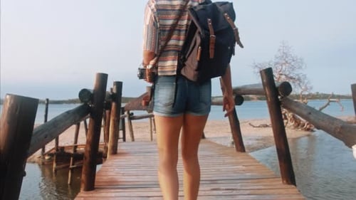 Young woman photographs scenic island bridge view with vintage film camera