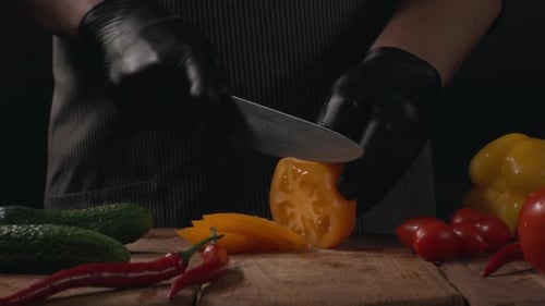 Person cuts a yellow tomato with a knife