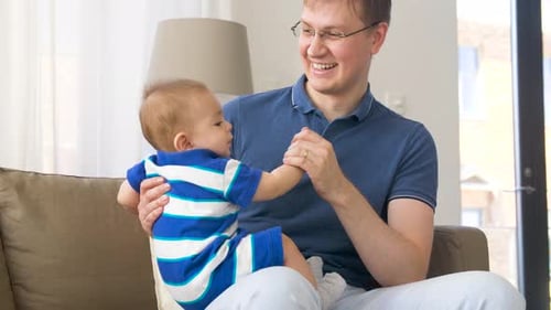 Loving father holding his baby boy on couch