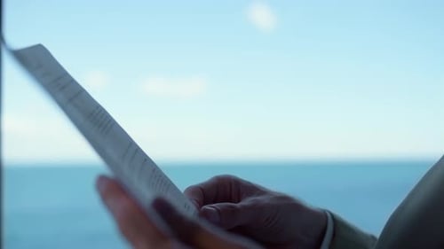 Businessman hands reading papers at ocean view hotel panoramic window workplace