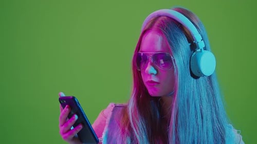 Green ScreenTeenage Girl In Neon Lights While Browsing Social Media On Her Mobile Phone