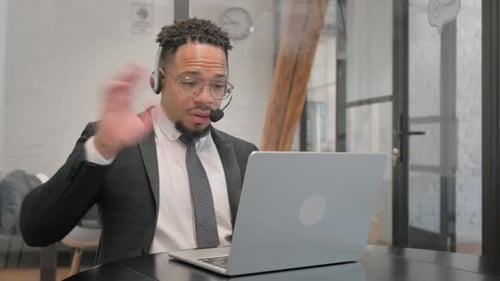 Multiracial Businessman with Headset in Call Center Doing Video Chat via Laptop