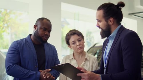 Portrait of Happy Salesman Talking with Clients Showcasing Dealership Vehicle